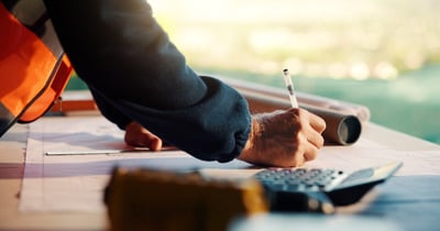 Construction worker writing on blue prints